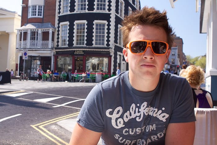 A portrait of a man in sunglasses posing on a city street, shot using a polarizer filter