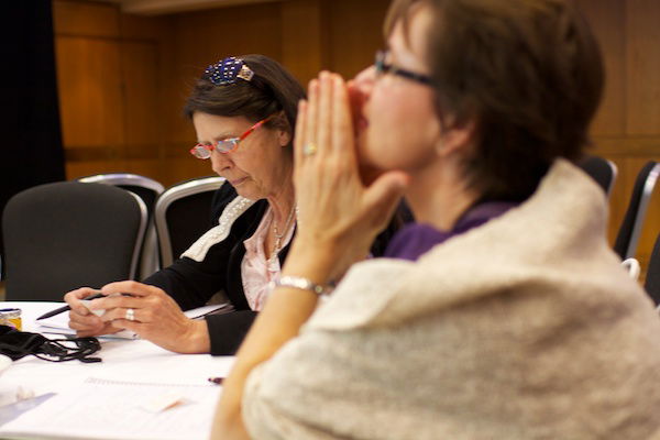 A selective focus photograph of two women sitting at a table - Corporate Event Photography