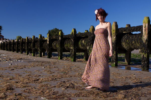 Portrait of a female model posing outdoors in front of a wooden structure, demonstrating the use of vertical lines in photography composition