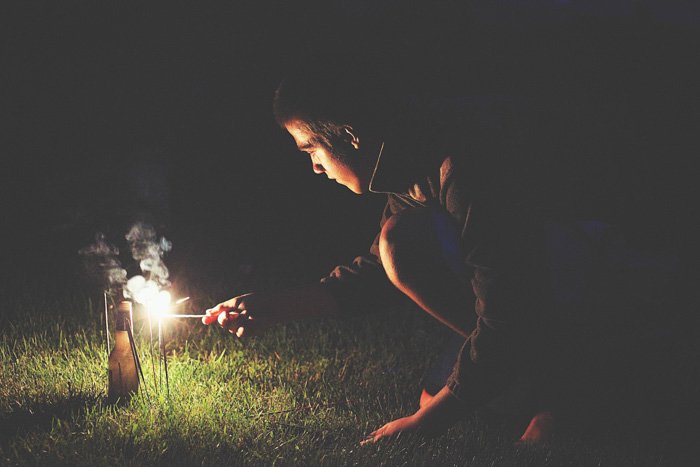 Atmospheric night portrait of a man lighting sparklers outdoors