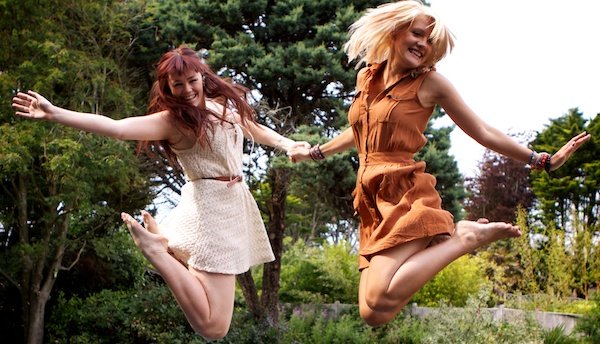 Photo of two young women jumping while holding hands