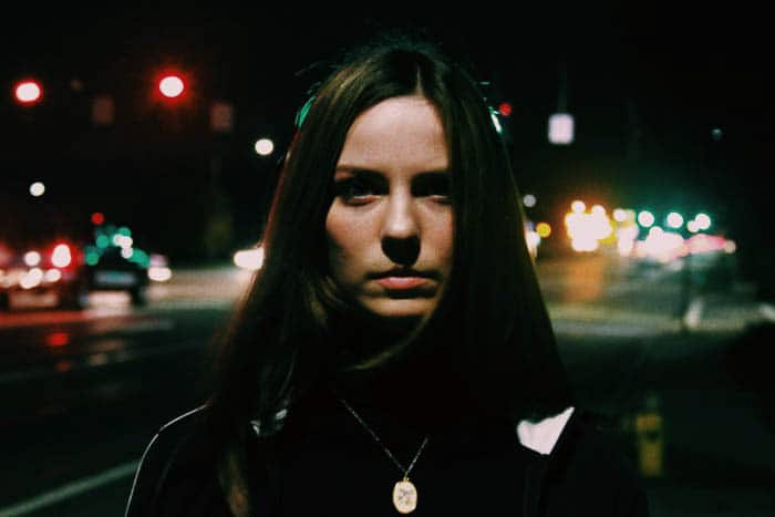 A night portrait of a female model on a street at night shot at a high ISO 3200, for 1/6 of a second at f/5