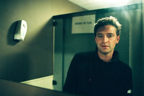 A portrait of a male model looking in a bathroom mirror, showing the use of triangles in photography composition 