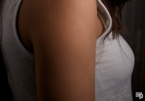 The shoulder of a women in a white tank top 