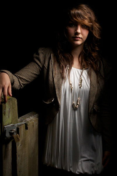 Atmospheric portrait of a girl posing by a fence at night 