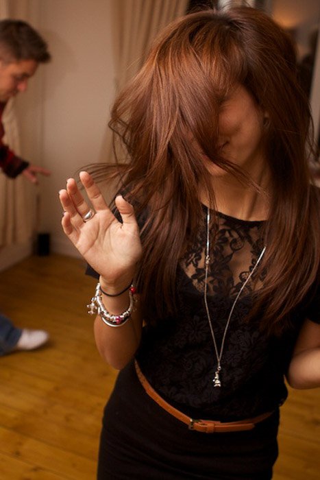 A brown haired female dancing indoors - party photography tips