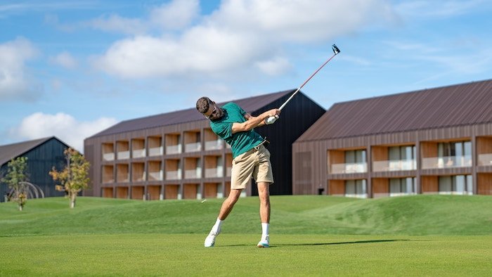 A frozen shot of a golfer mid-swing on a golf course green