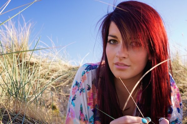 红发女孩躺在草地上，对着镜头微笑