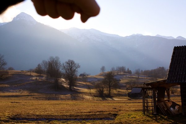 a hand blocking the sun with slovenian mountains in the background
