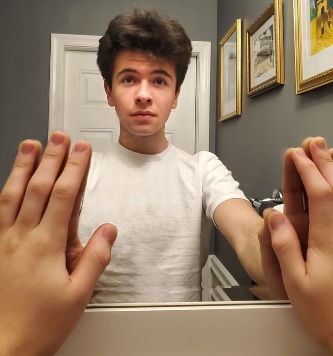 Photo of a guy touching a mirror with both hands without the phone showing