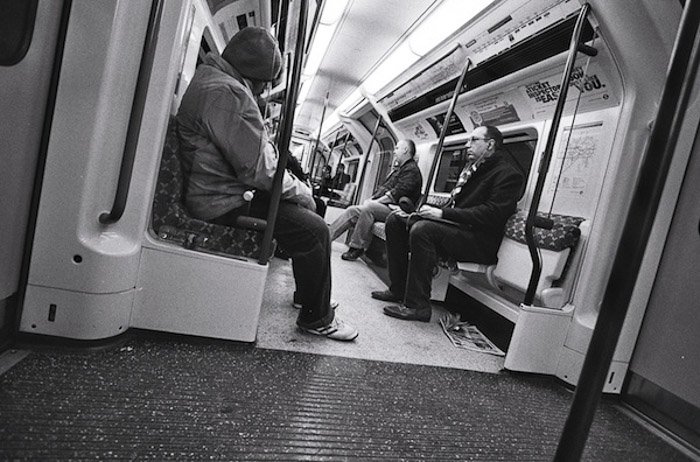 A black and white image of people on a subway - shoot from the hip photography