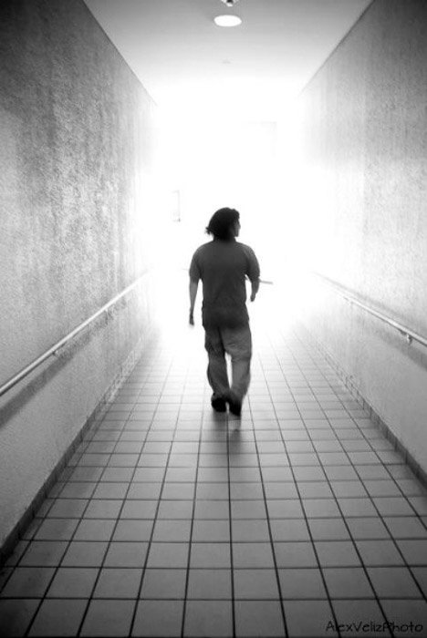 A black and white photo of a man walking down a corridor