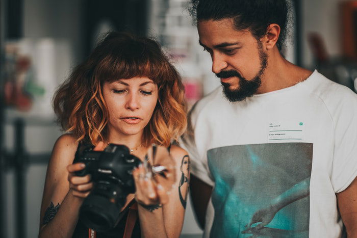 Woman holding a camera and showing the screen to the man next to her