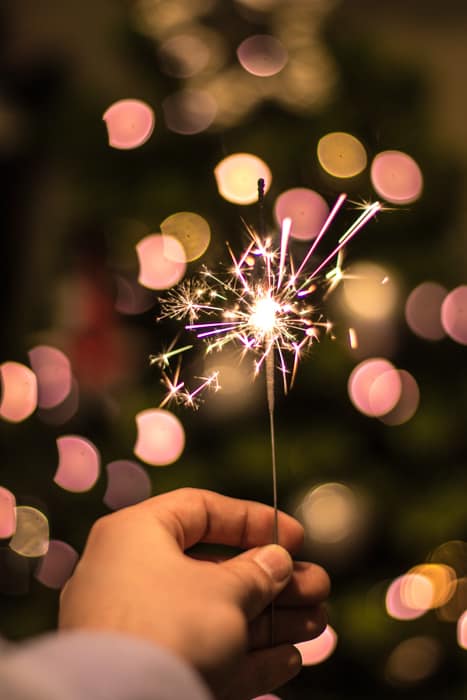 A close up christmas photography shot of someone holding a sparkler
