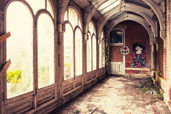 Dirty corridor of an old boarding school building with big windows and natural light and cute graffiti on the back wall