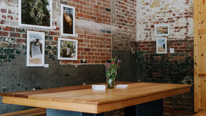 A wooden table in a rustically designed room with framed photography on the wall