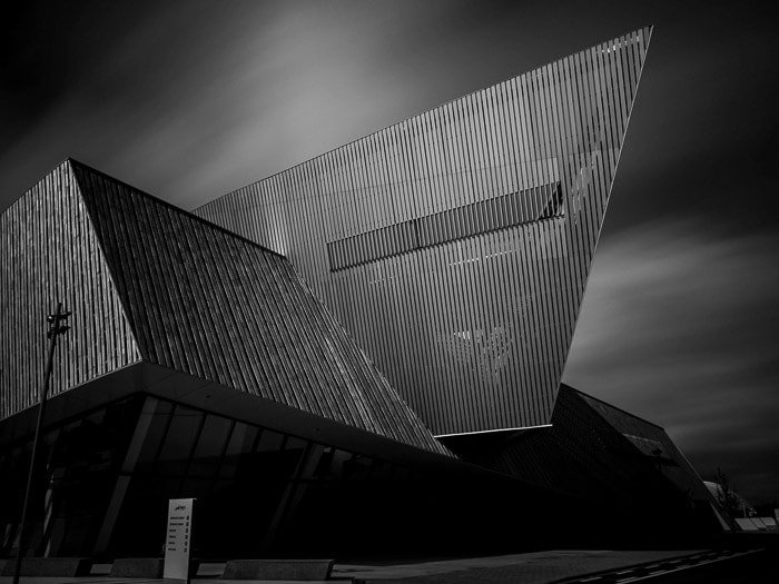 Black and white photo of the new congress center in Mons, Belgium with motion blur sky