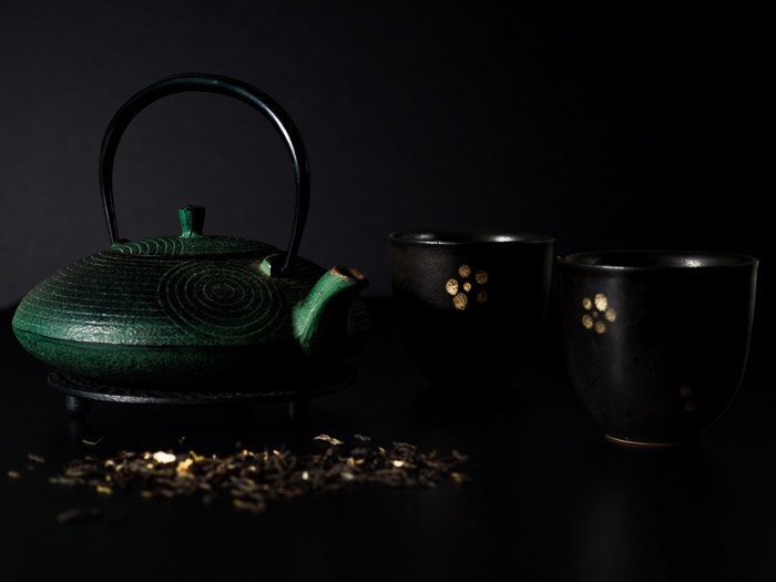 A dark, moody shot of a teapot and teacups for still life photography