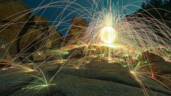 A glowing ball with colored sparks being emitted from Steel Wool Spark Photography