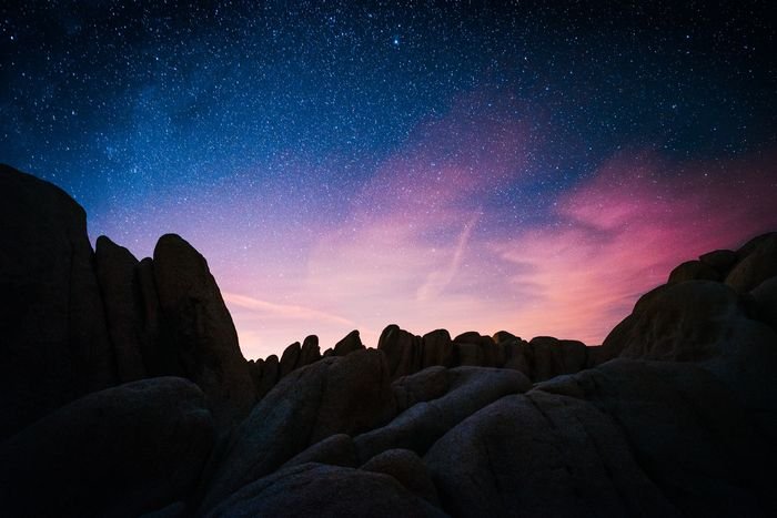 Photo of the starry sky above mountains at night as an example of creative landscape photos