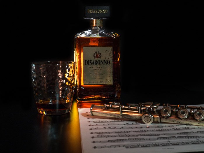Atmospheric still life photography shoot of a clarinet and bottle of Disaronno