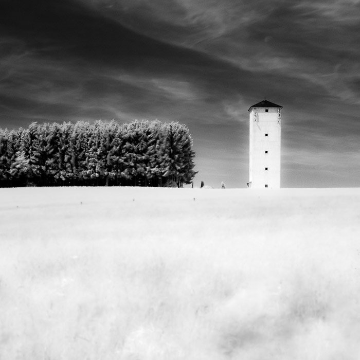 An infrared photography shot of a tower in the countryside, demonstrating symmetry in photography 