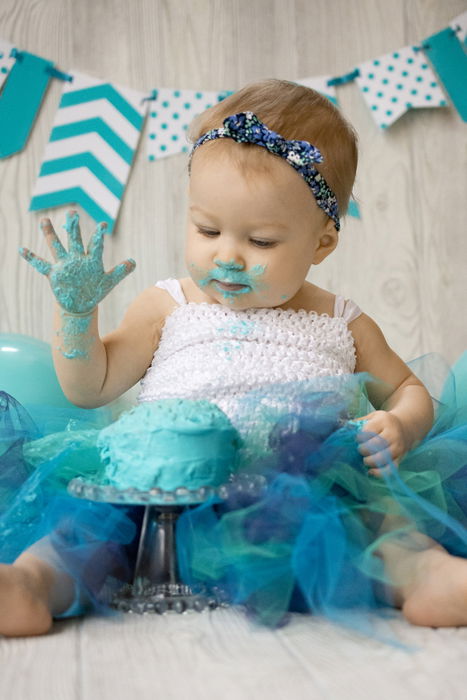 Cute diy cake smash photo shoot of a young baby smashing a green cake 