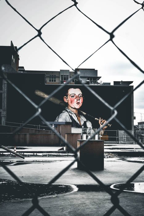 A street photo of graffiti shot through a chain link fence with a 50mm lens
