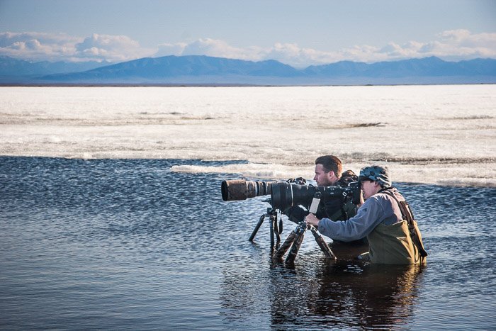 Two nature photographers setting up to photograph birds in water