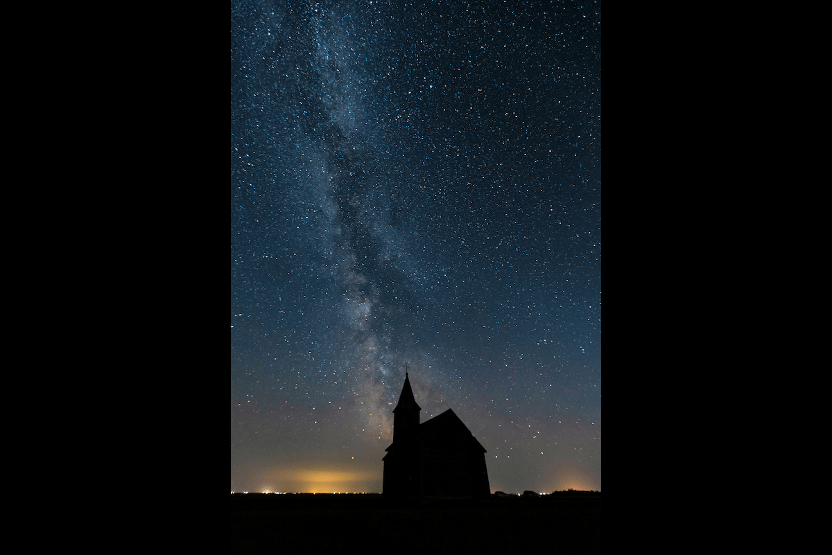 A church silhouette against a starry sky taken with milky way photography gear