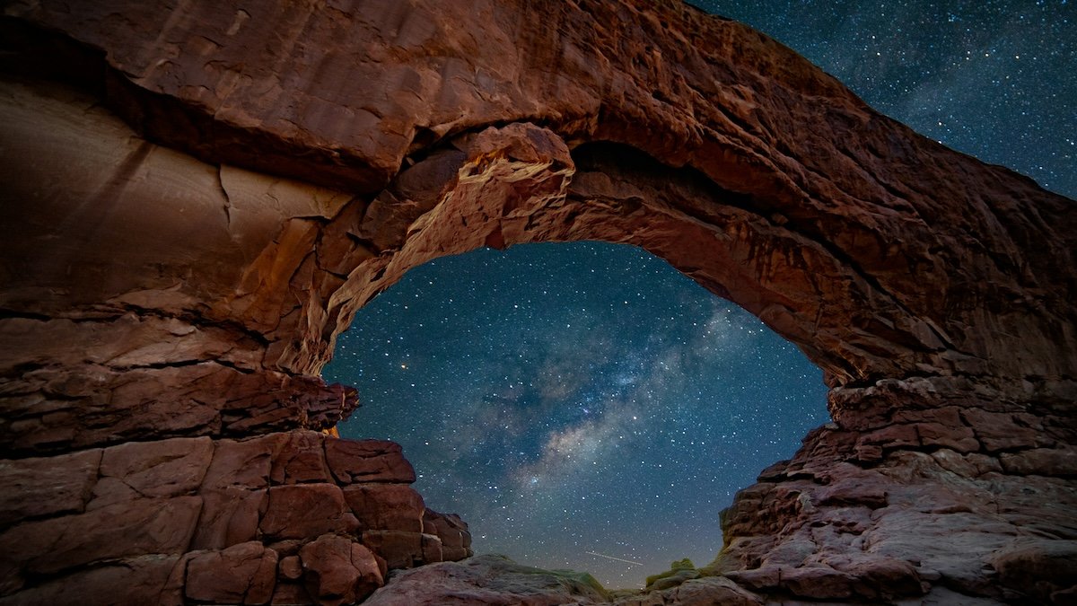 Stars at night through a stone arch take with milky way photography gear