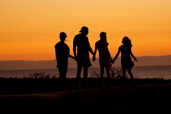 The silhouette of a family of four aginst a sunset sky 
