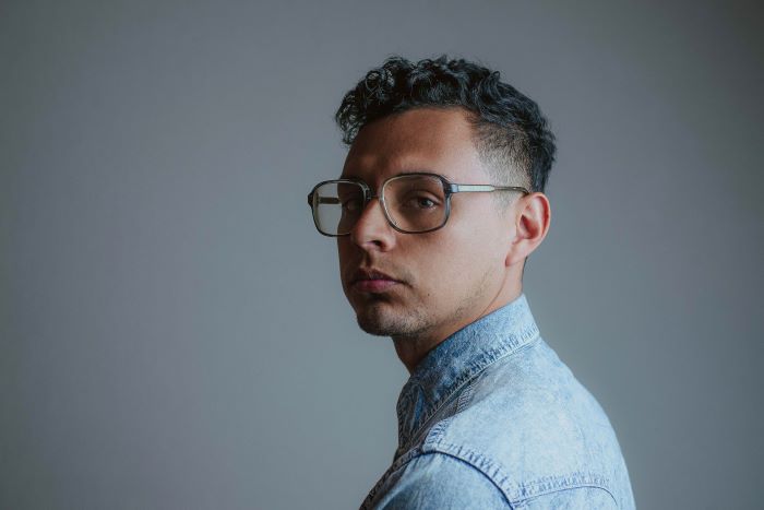 Portrait of a man wearing glasses in front of a grey background