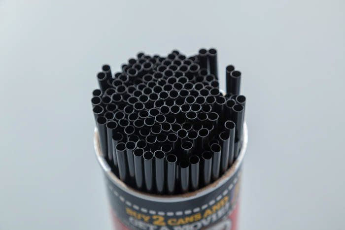 A can of Pringles full of black straws 