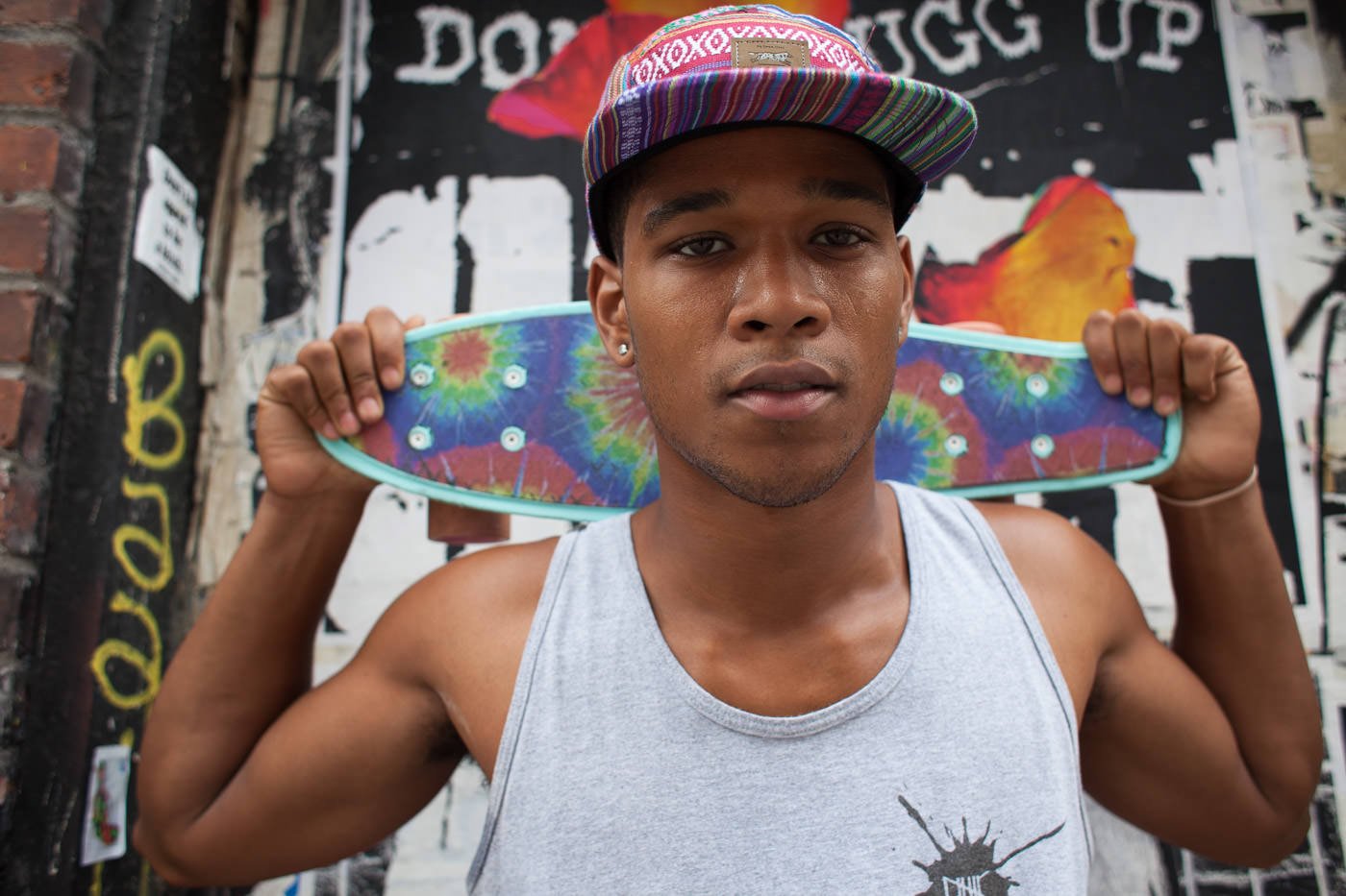 Street photography: Portrait of young man holding skateboard behind his head
