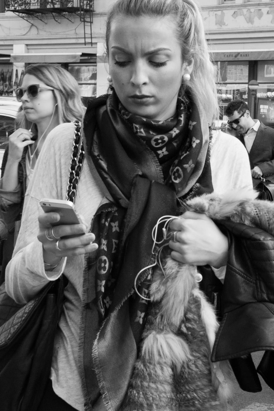 Street photography: Black and white portrait of ponytailed woman checking her phone