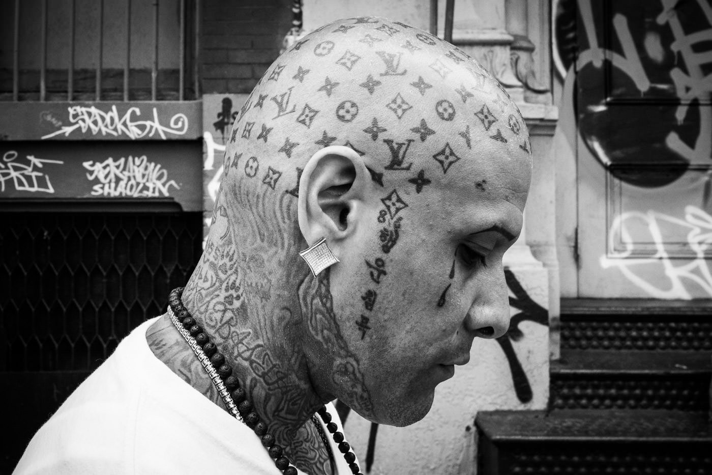 Street photography: portrait of man in profile showing elaborate head tattoos