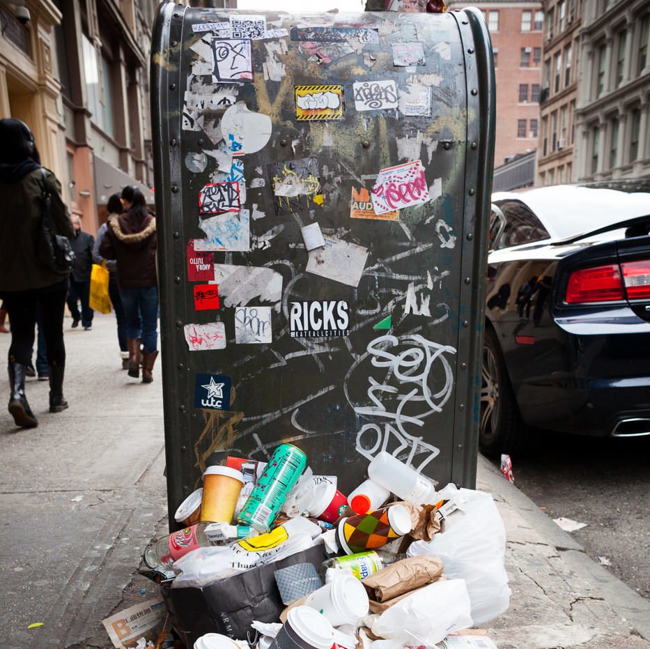Street photography: Mailbox covered in graffiti and stickers with pile of trash in foreground