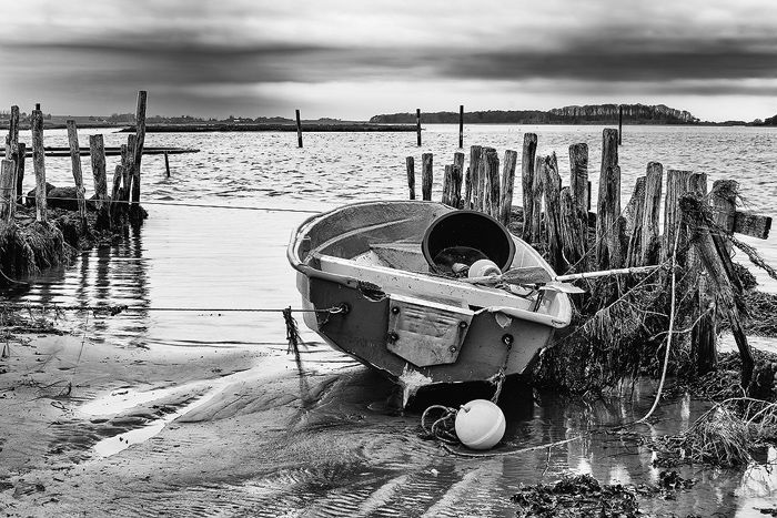 Black and white coastal photo showing small boat at low tide