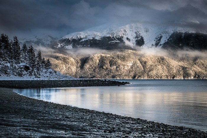 Coastal photography: rocky coastline with snow-capped mountain in background