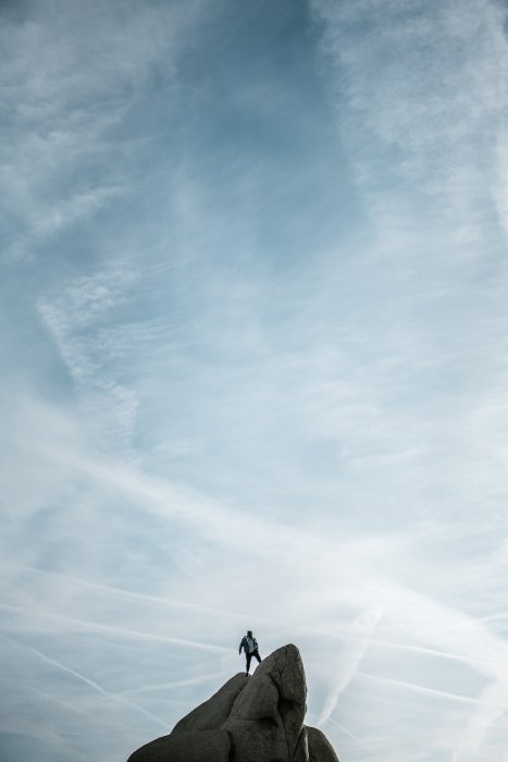 El espacio negativo en la fotografía - Una persona de pie sobre una roca, con un cielo azul detrás de ellos. 