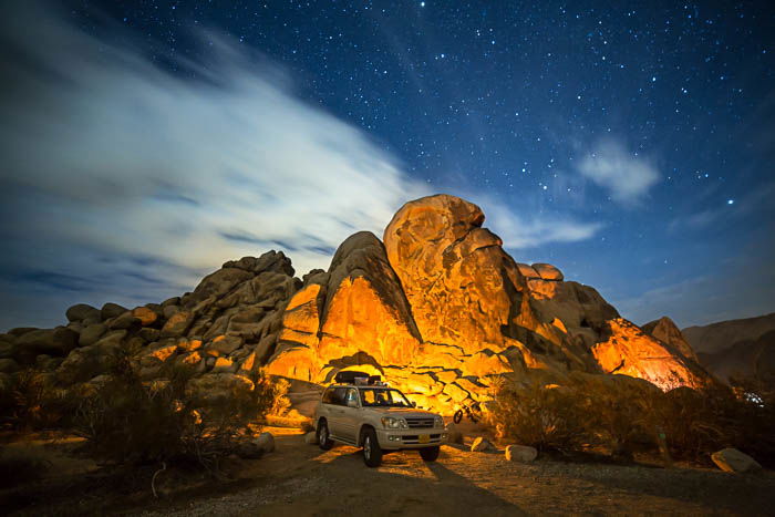 Picture at Joshua Tree National Park in California, showing a white car in front of tall rocks.