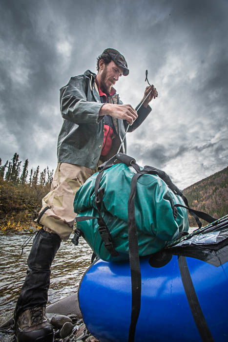 Low perspective photo of a man packing a raft.