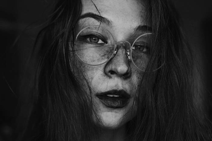 Creative female self-portrait wearing round glasses.