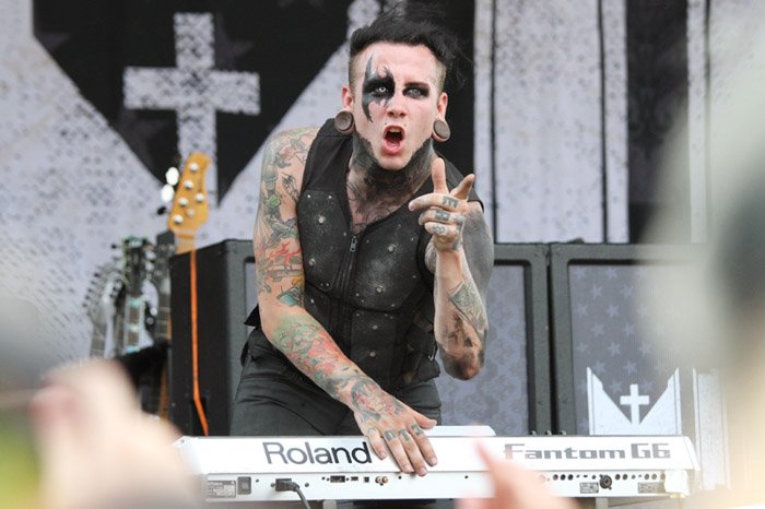 Motionless in White keyboard player gesturing to crowd at an outdoor concert.