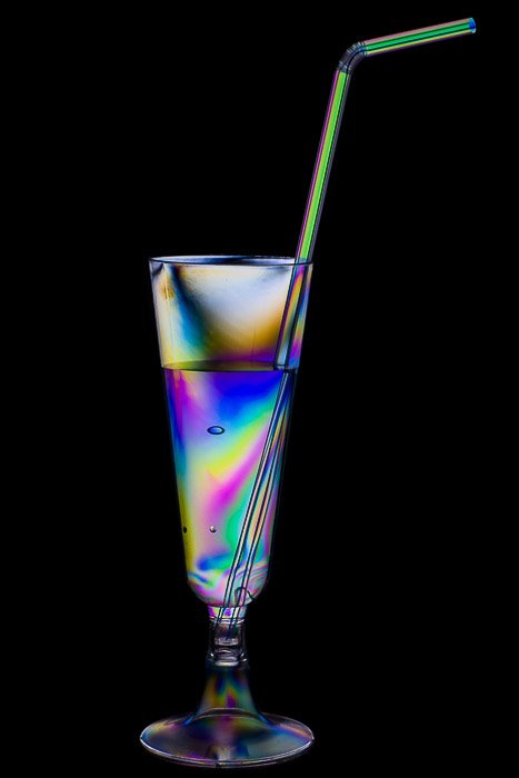 Rainbow effect on a plastic cocktail glass and drinking straw.