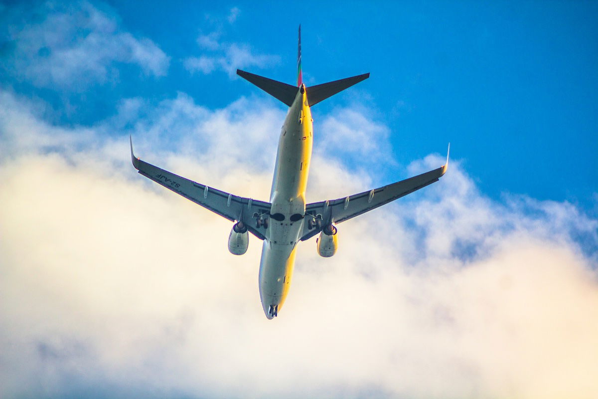 An airplane flying against white clouds and a blue sky as an example of aviation photography