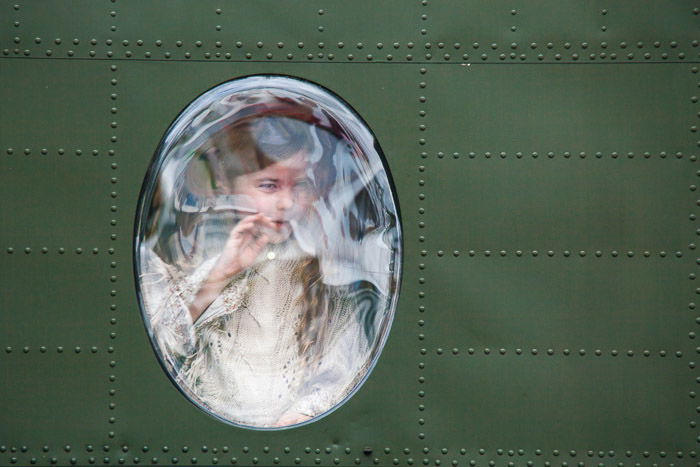 Young girl looking out the window of a military jet.