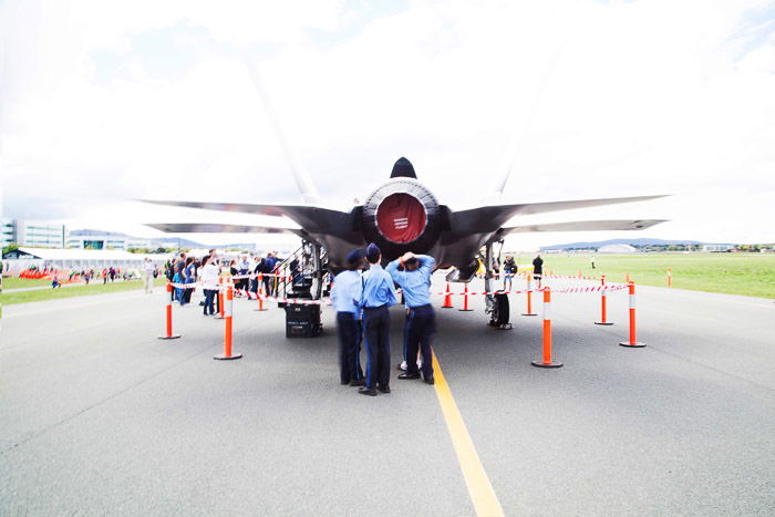 Team examining engine of fighter jet