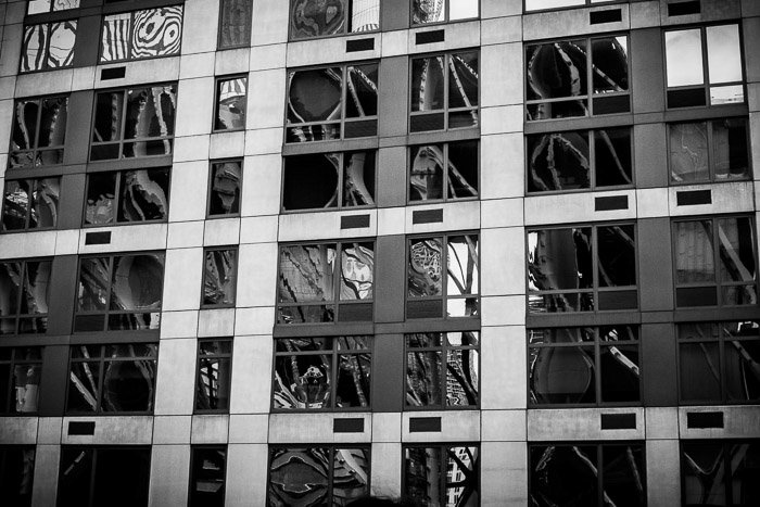 Distorted reflections in the windows of a high-rise building. Urban street photography. Monochrome reflections.